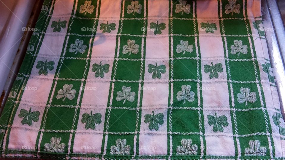 Symmetrical pattern of shamrocks on a St Patrick's day themed kitchen towel.