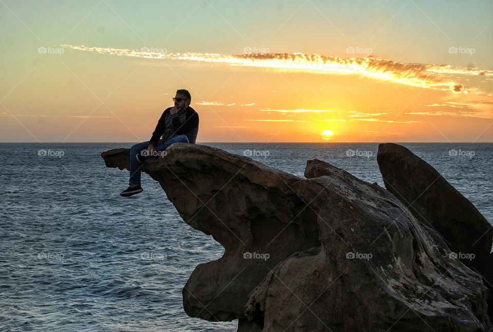 Sit on the rocks of the sea during sunset