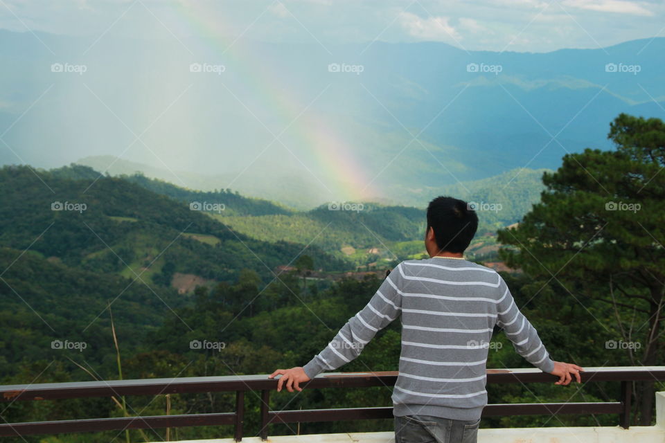 One man looking the rainbow in nature after the rain.