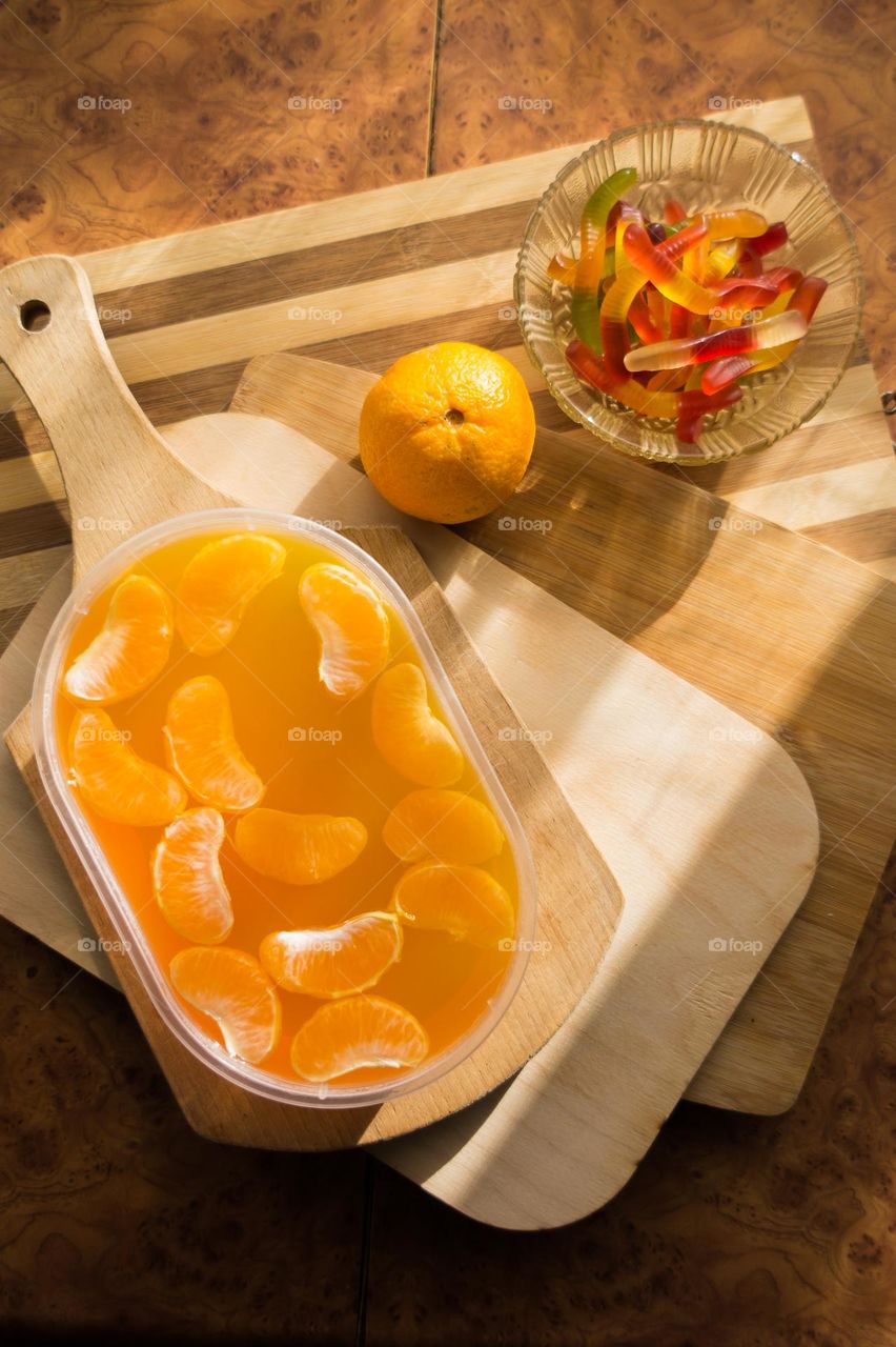 Delicious orange jelly with tangerine slices in a container and jelly worms.