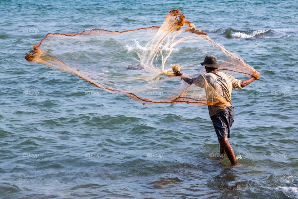 Fisherman throws net. Traditional style fishing in Cambodia. Fisherman throws net to the sea hoping to catch a fish.