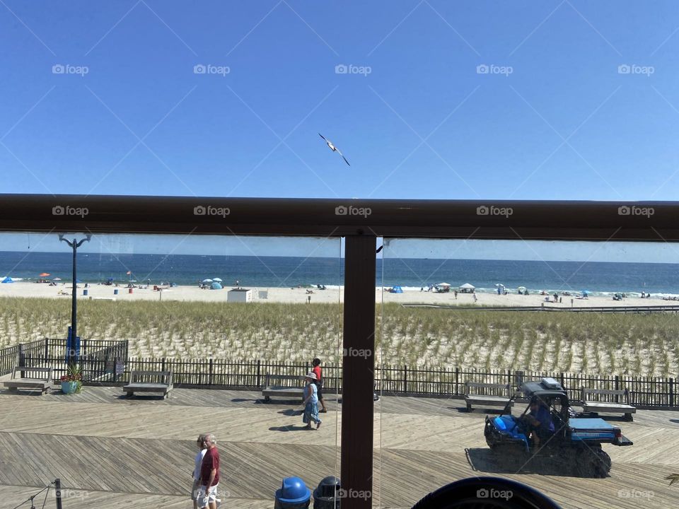 People strolling on the boardwalk in Seaside Heights, NJ in a photo taken from the outdoor balcony seating at Spicy Cantina, a Mexican restaurant. It’s a great place view the boardwalk, beach and ocean while enjoying lunch and a Margarita.