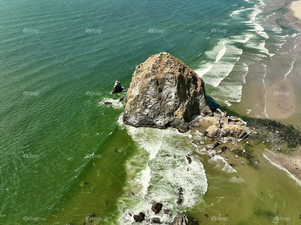 Haystack Rock standing tall amidst the serene beauty of Cannon Beach, where tide pools meet the endless horizon