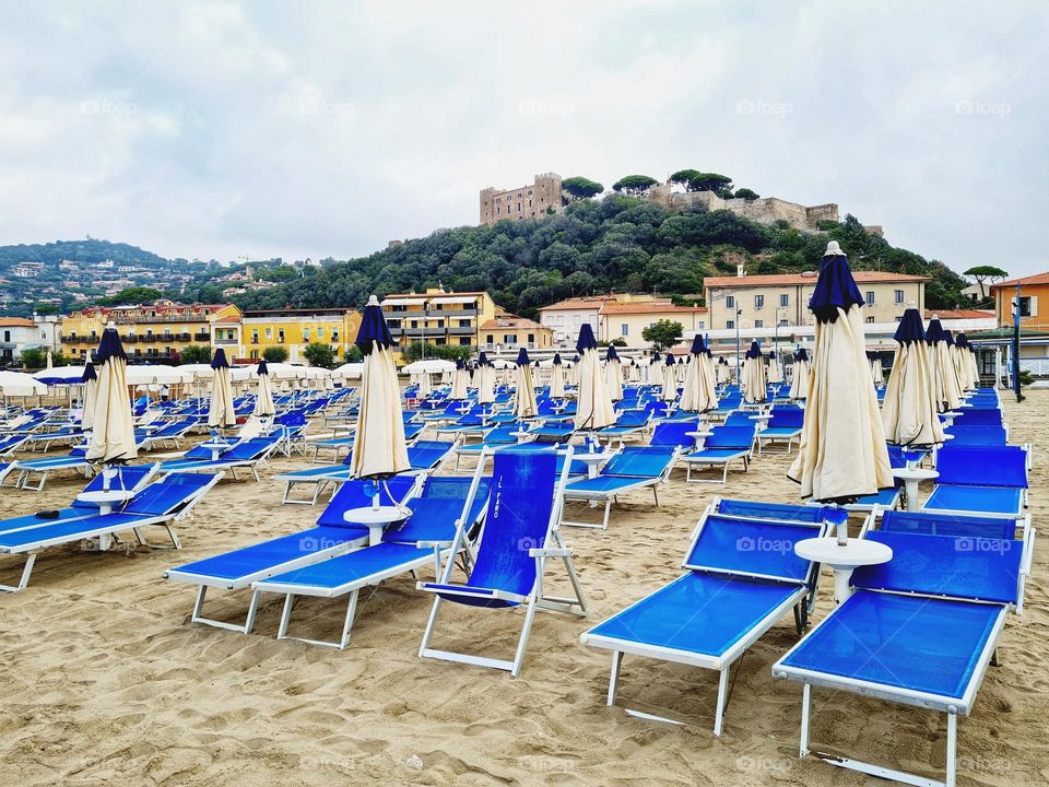 empty bathing establishment and in the distance Aragonese Castle of Castiglione della Pescaia in Tuscany