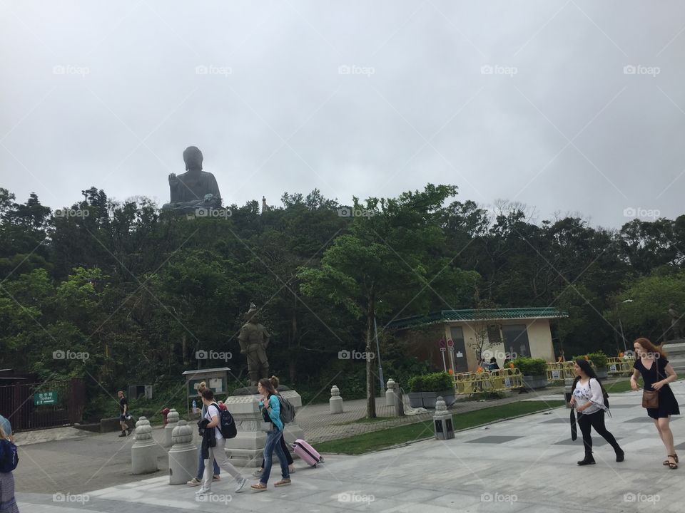 “Chinese Zodiac Warrior Statue symbolizing the Horse Chinese Zodiac Year, with Tourists, and Buddha in Peace, Harmony and One with Nature & Creation Ngong Ping, Lantau Island, Hong Kong. Copyright Chelsea Merkley Photography 2019.”