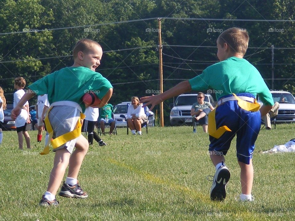 2 young boys running while playing flag football