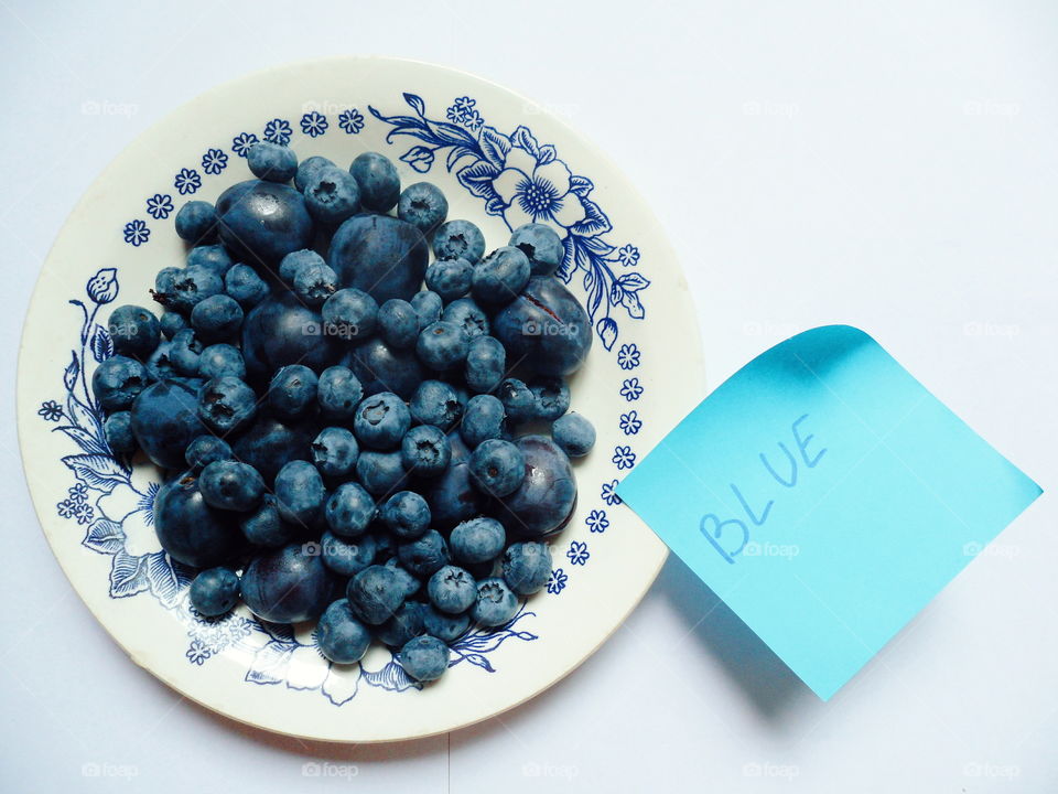 Berries of blueberries and plums on a white plate