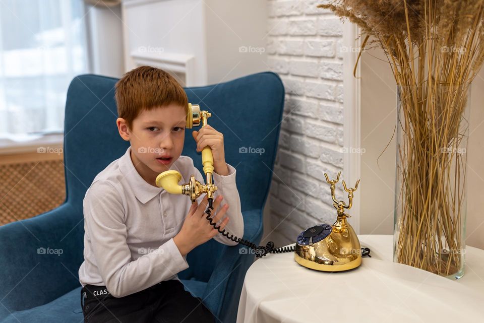 Child red-haired boy plays and talk retro phone