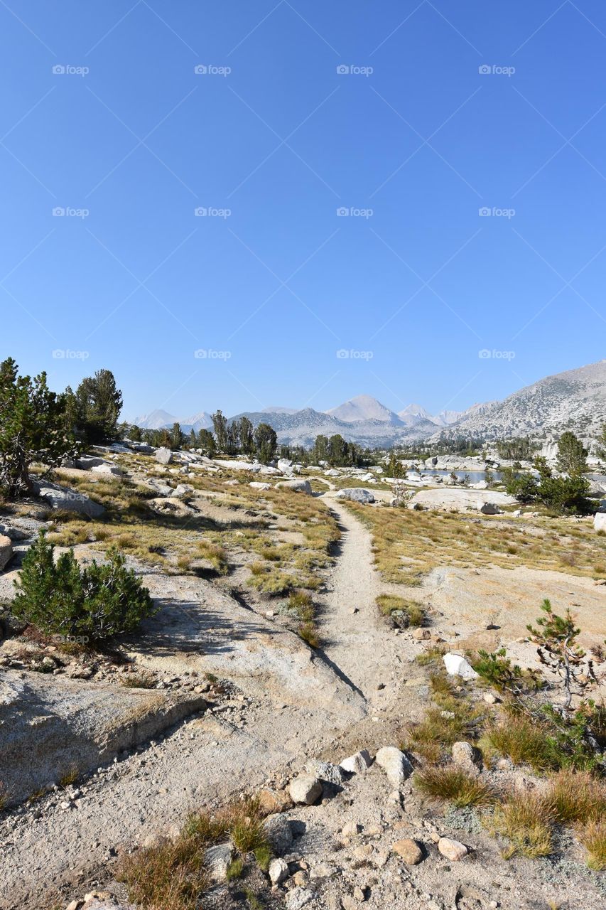 A thin dirt trail welcomes you to the dramatic mountain landscape