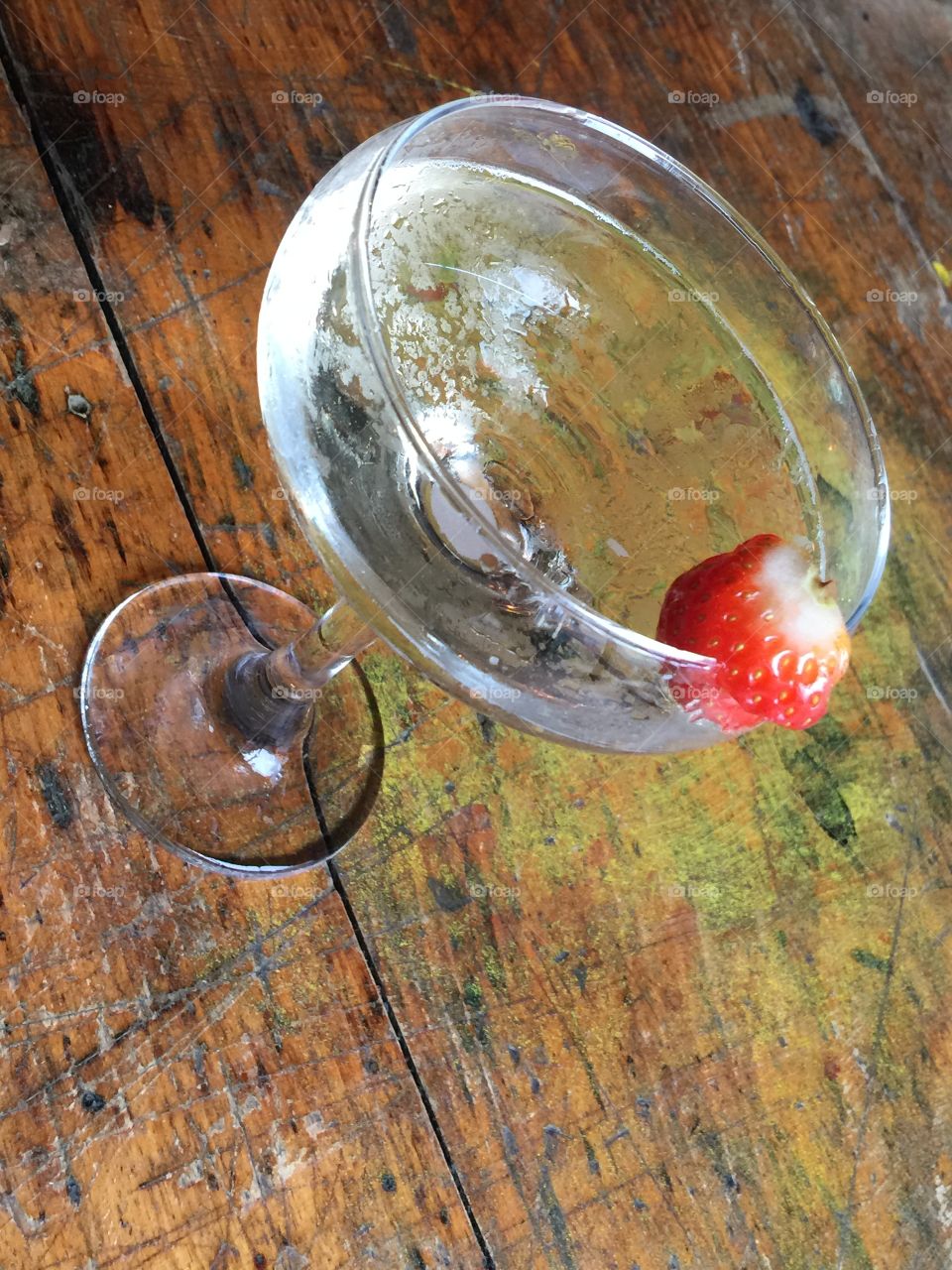 Cocktail glass with strawberry on scrubbed pine bar table 