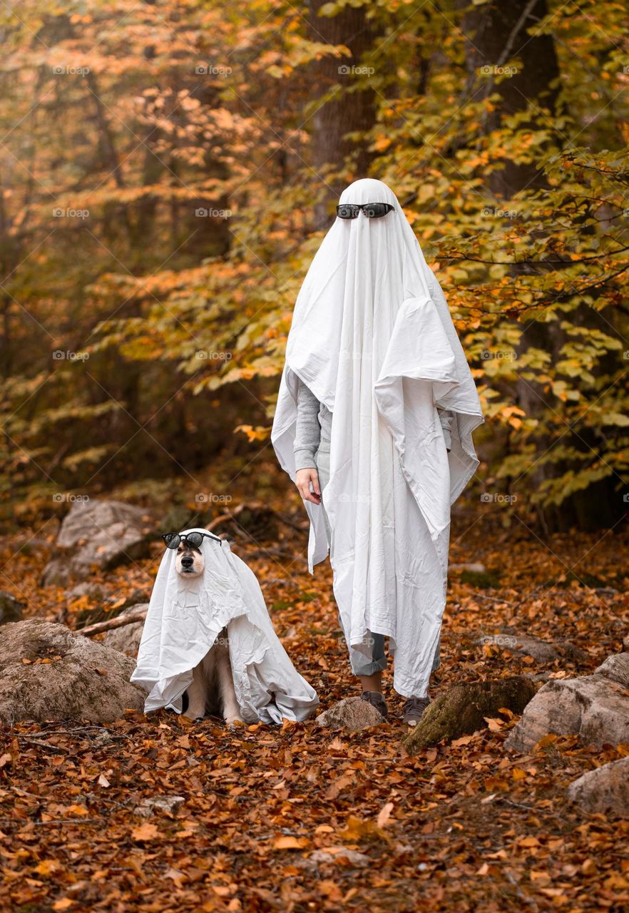 A dog and woman dressed up as ghosts
