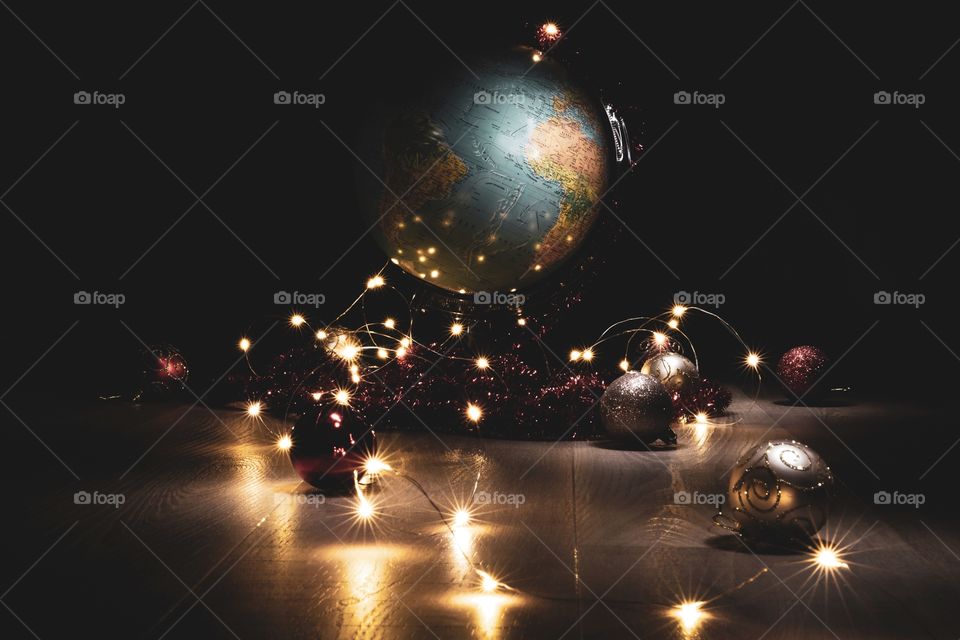 Christmas around the world. a portrait of a globe surrounded by fairy lights and christmas balls.