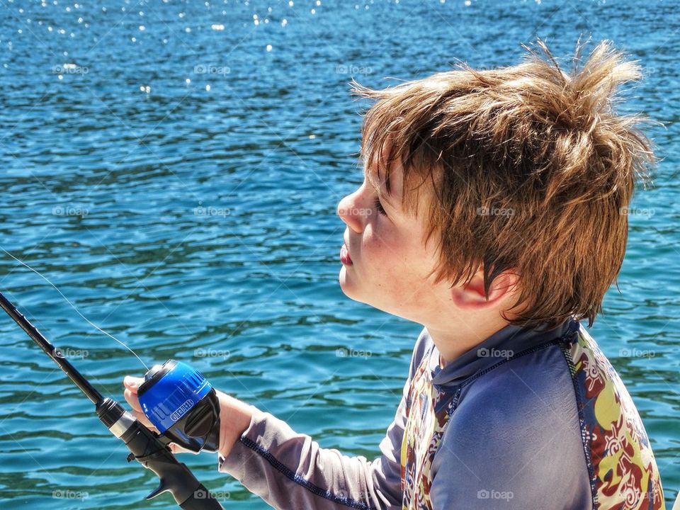 Young Boy Fishing On A Blue Lake
