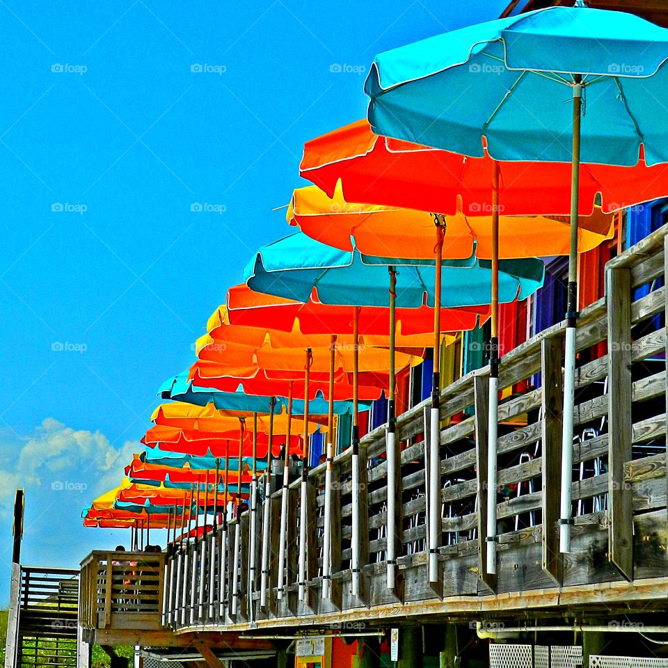 Clash of colors - Beautifully colored umbrellas sitting on a deck with a blue sky background