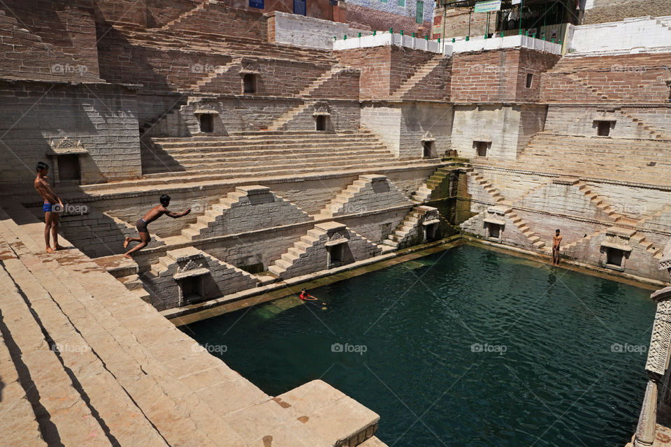 A boy jumps in a step well in jodhpur Rajasthan, India. Step well is known as Toorji ka jhalra.