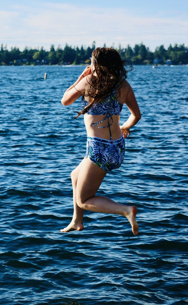 A young woman jumps into the cool blue waters of American Lake in Tillicum, Washington State 