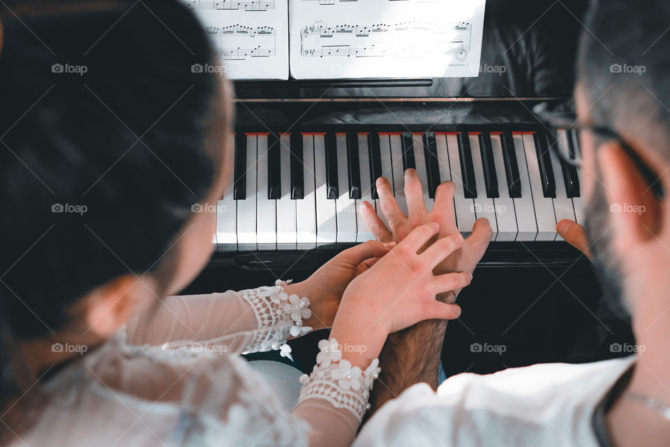 Girl teaches a pupil to play the piano