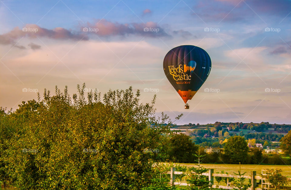 Leeds Castle hot air balloon in flight over the Kent countryside in late afternoon 