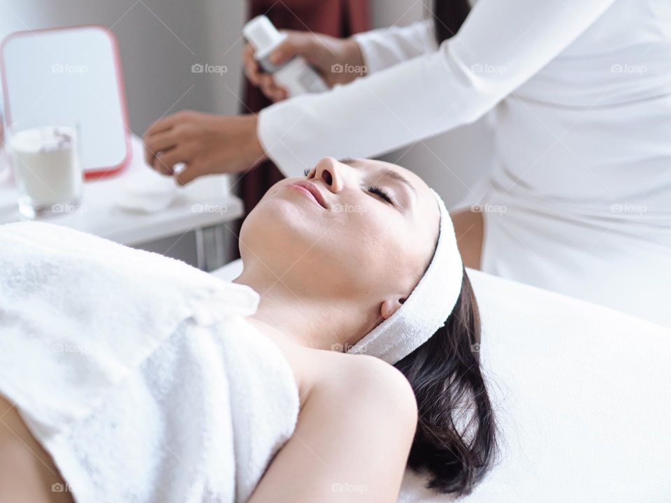 Young beautiful woman with brunette hair doing cosmetologist procedures, skin care