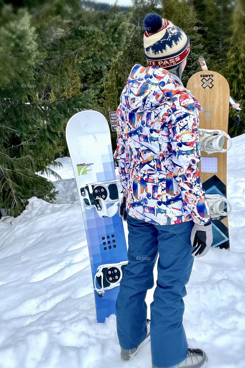 A female snowboarder gets prepped to ride the ski lift on a beautiful clear day in Washington State at White Pass