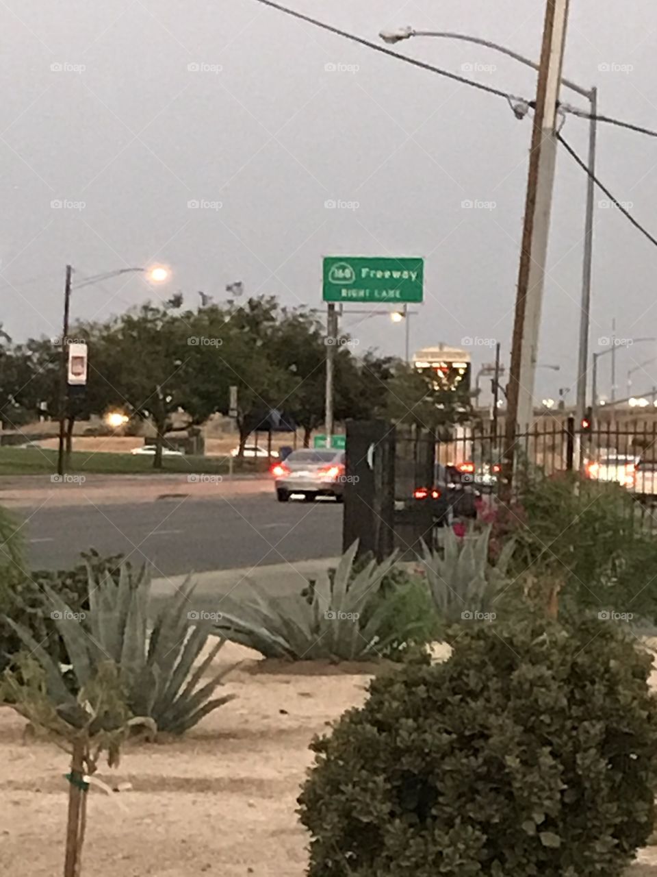 Freeway sign and traffic in the evening time. The street near the freeway entrances and exits is always busy. Everyone wants to either take the freeway or leave it to reach his/her destination.