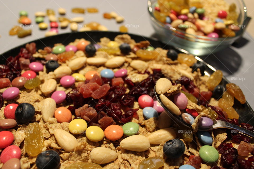 A bowl plate with chocolate candy,almonds,raspberry and dry fruits