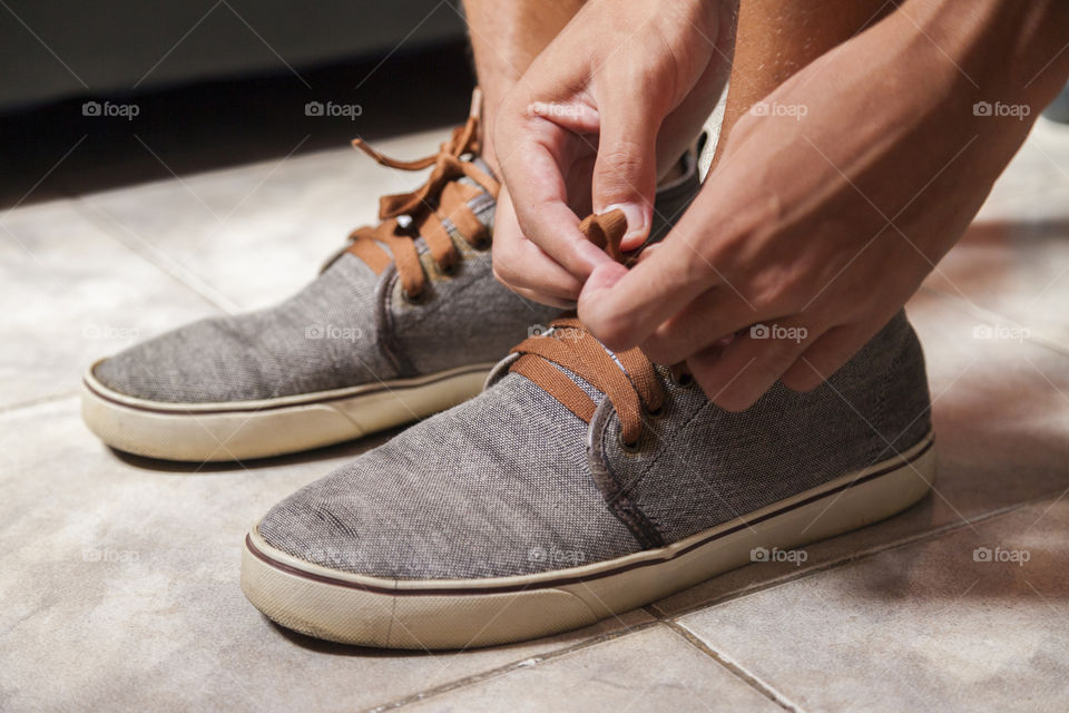Young sportsman tying up tennis before going out to do running exercise in the morning