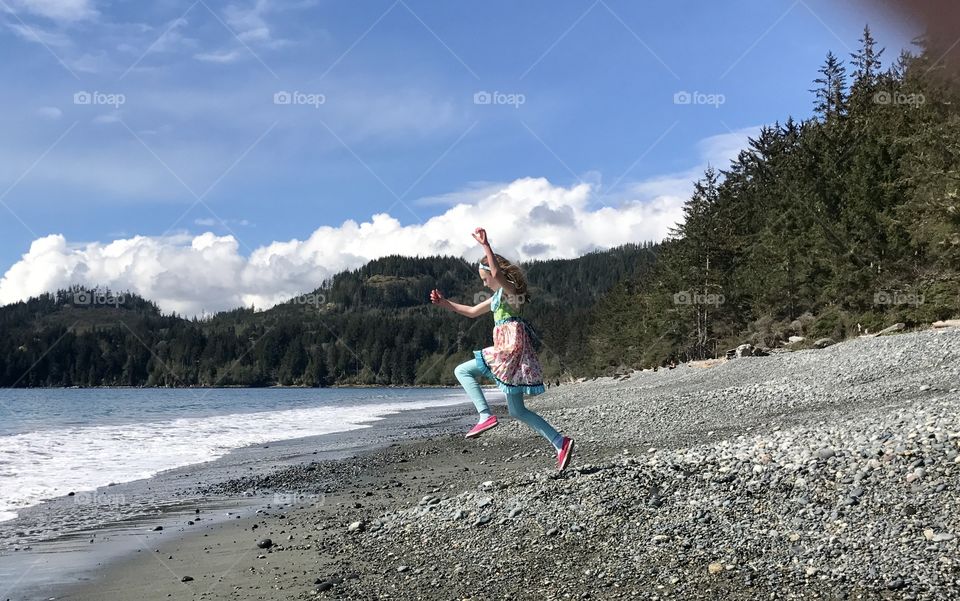 Girl playing on the beach, jumping running on the ocean shore