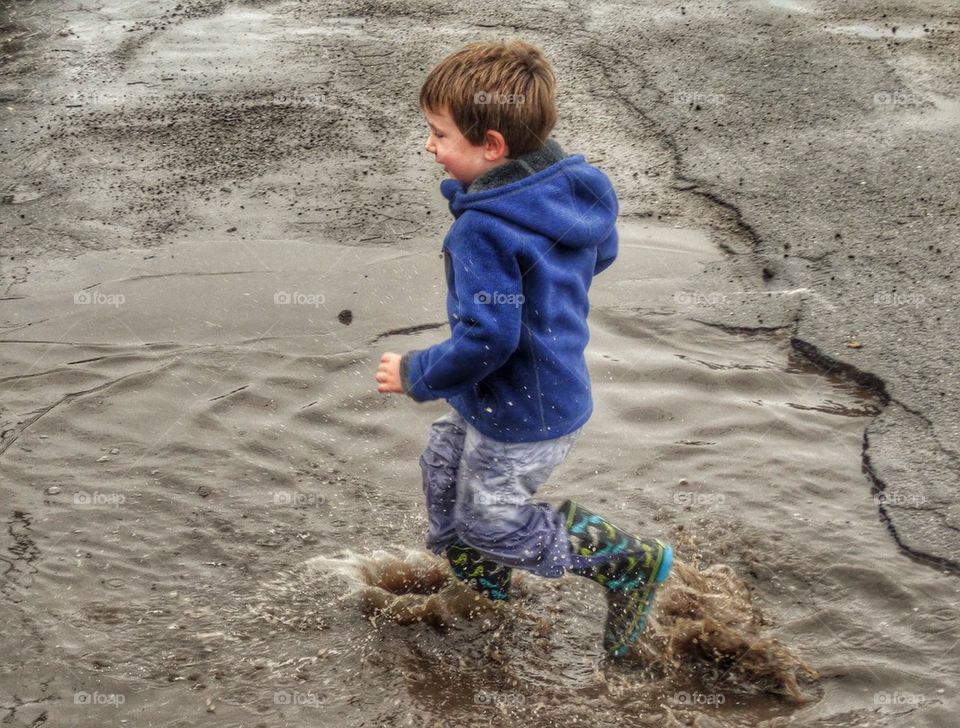 Boy Splashing In A Puddle