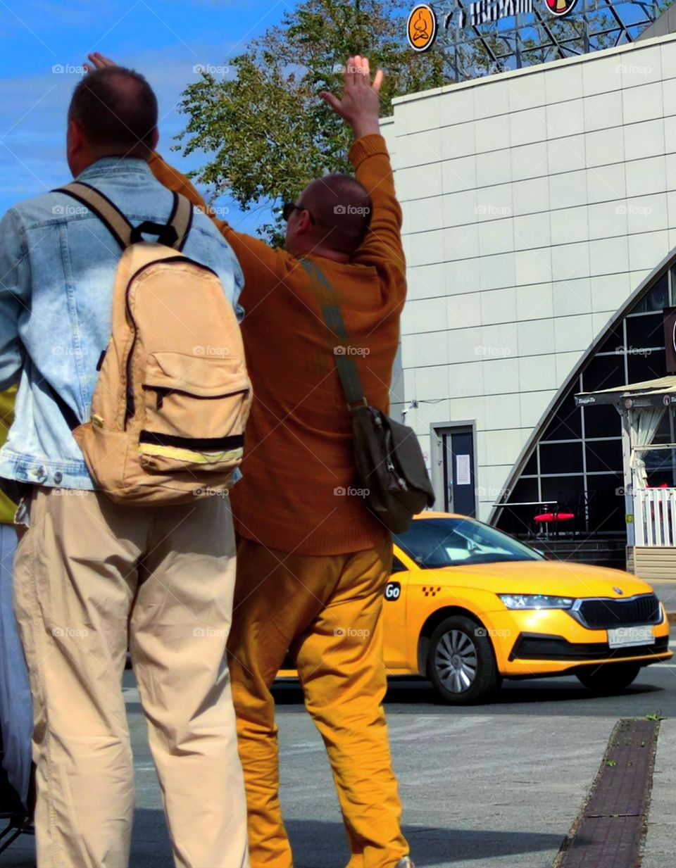 Yellow taxi on the road and men on the sidewalk