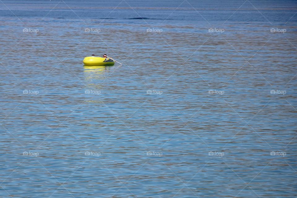 Little yellow rubber boat's floating on the sea