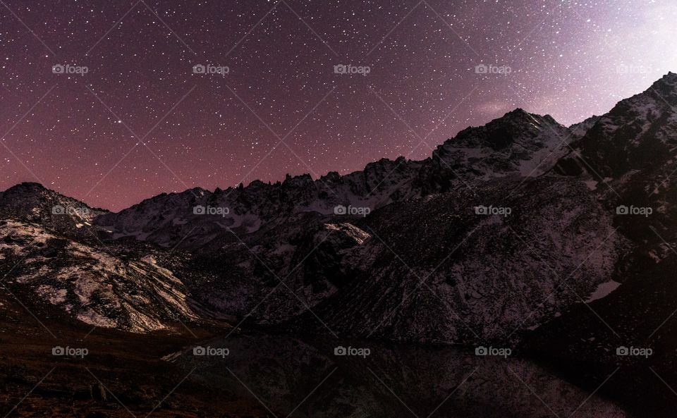 sky full of stars above snow capped mountains filled with moonlight