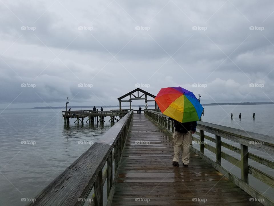 Rainbow umbrella man on pier
