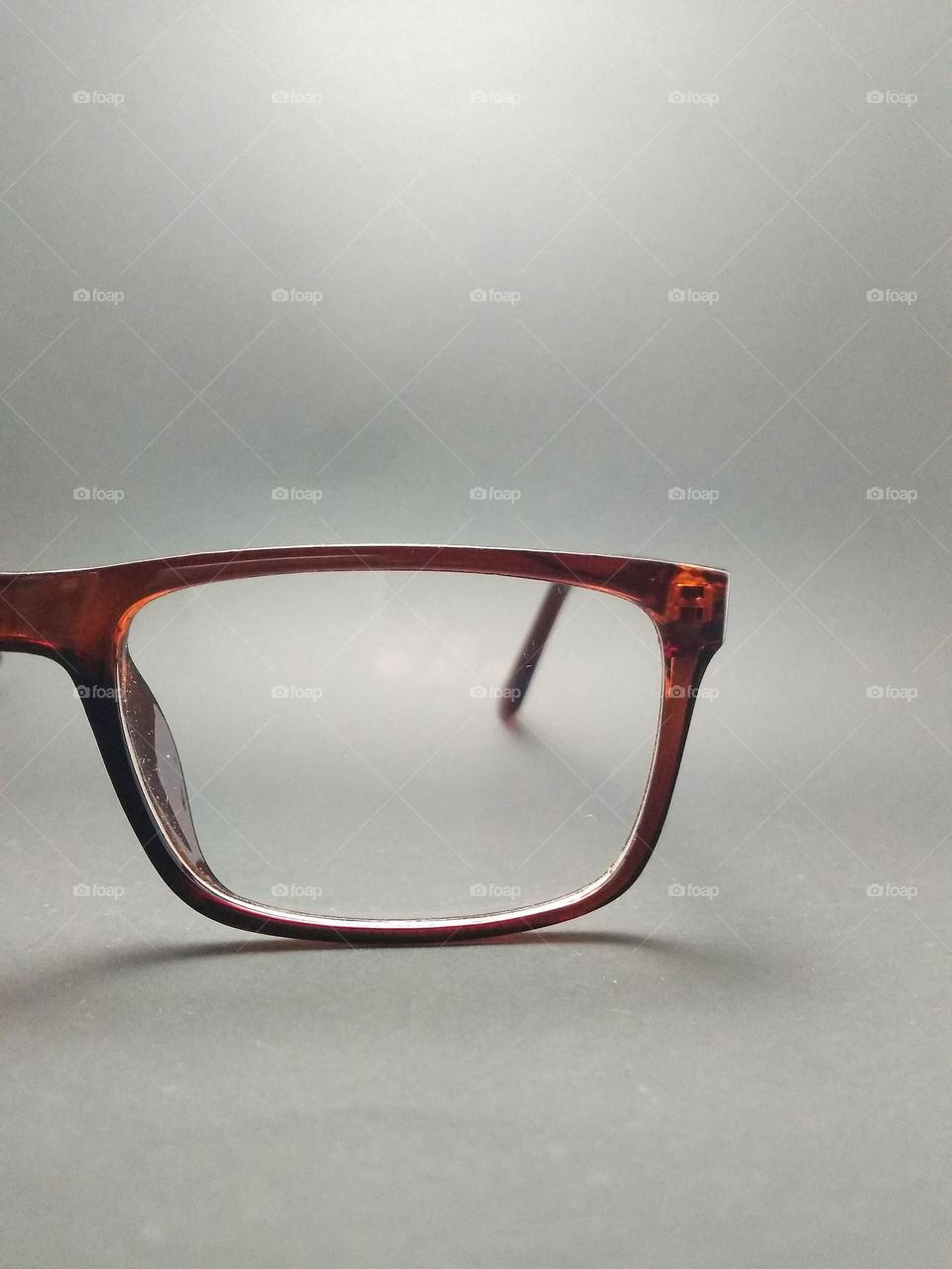 Reading glasses with brown frame transparent lenses photographed just to the left at close range.