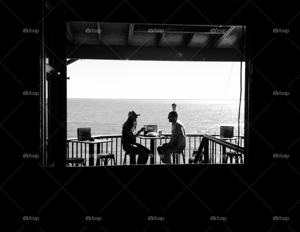 Couple sitting at a restaurant outside by a lake in silhouette and shadow