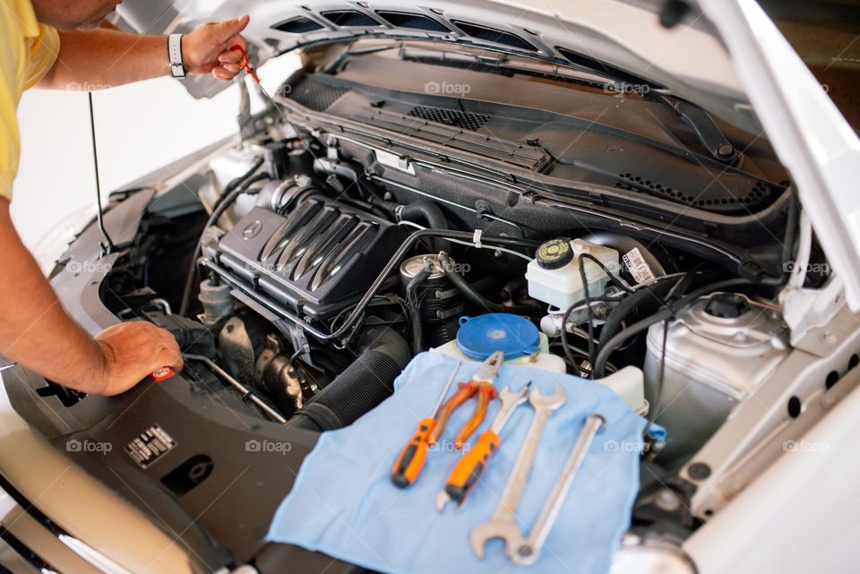 Mechanic checking oil levels on the car under the hood