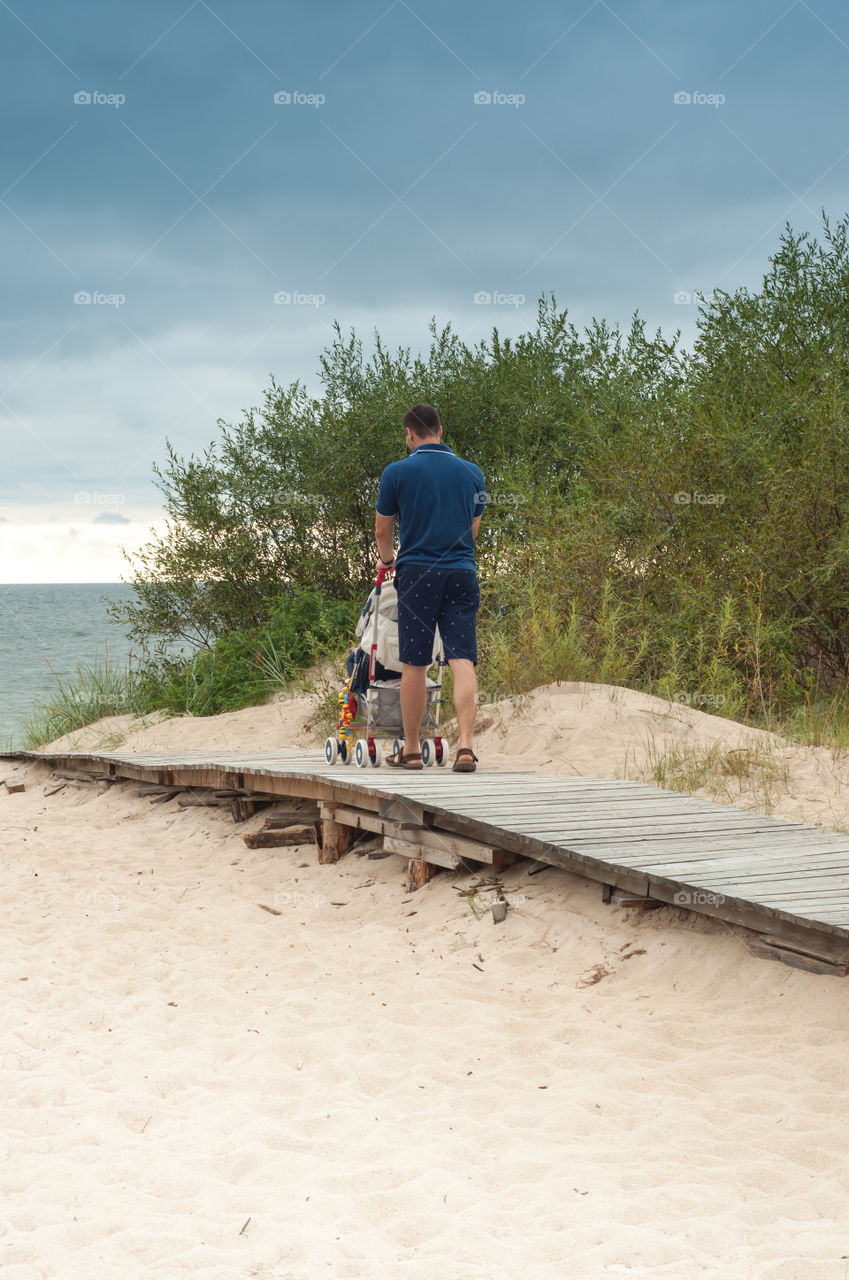 First trip to the sea daddy with baby carriage from behind 