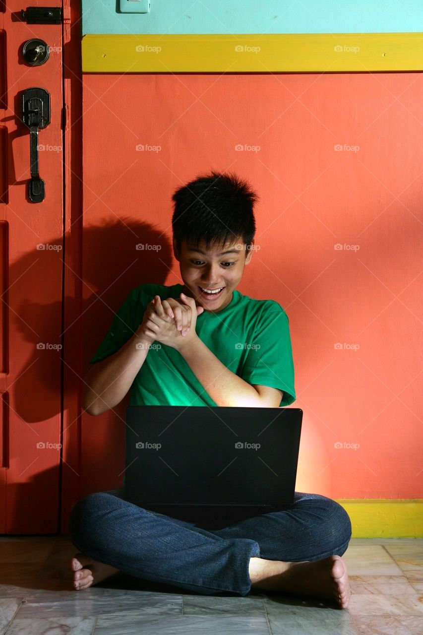 young asian teen with a laptop computer in a living room