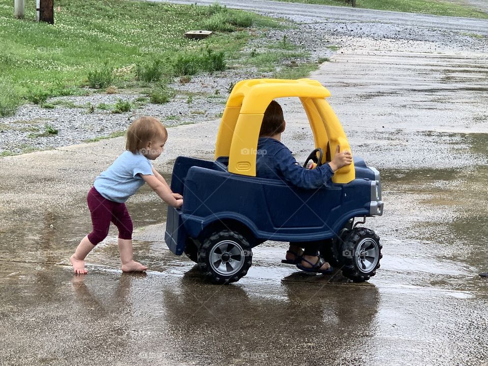 Helping big brother drive his little car in the rain, thinking she’s big stuff.
