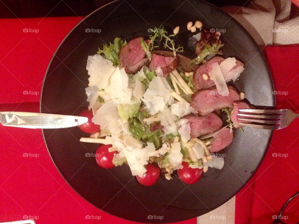 Hot salad with meat, tomatoes, parmesan and vegetables 