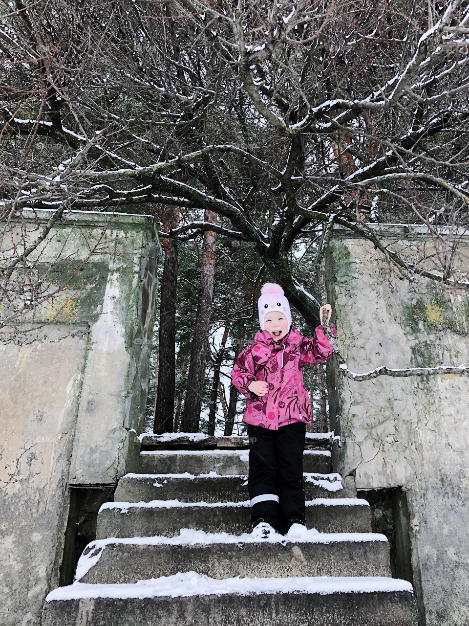 little girl in winter overalls walking and laughing