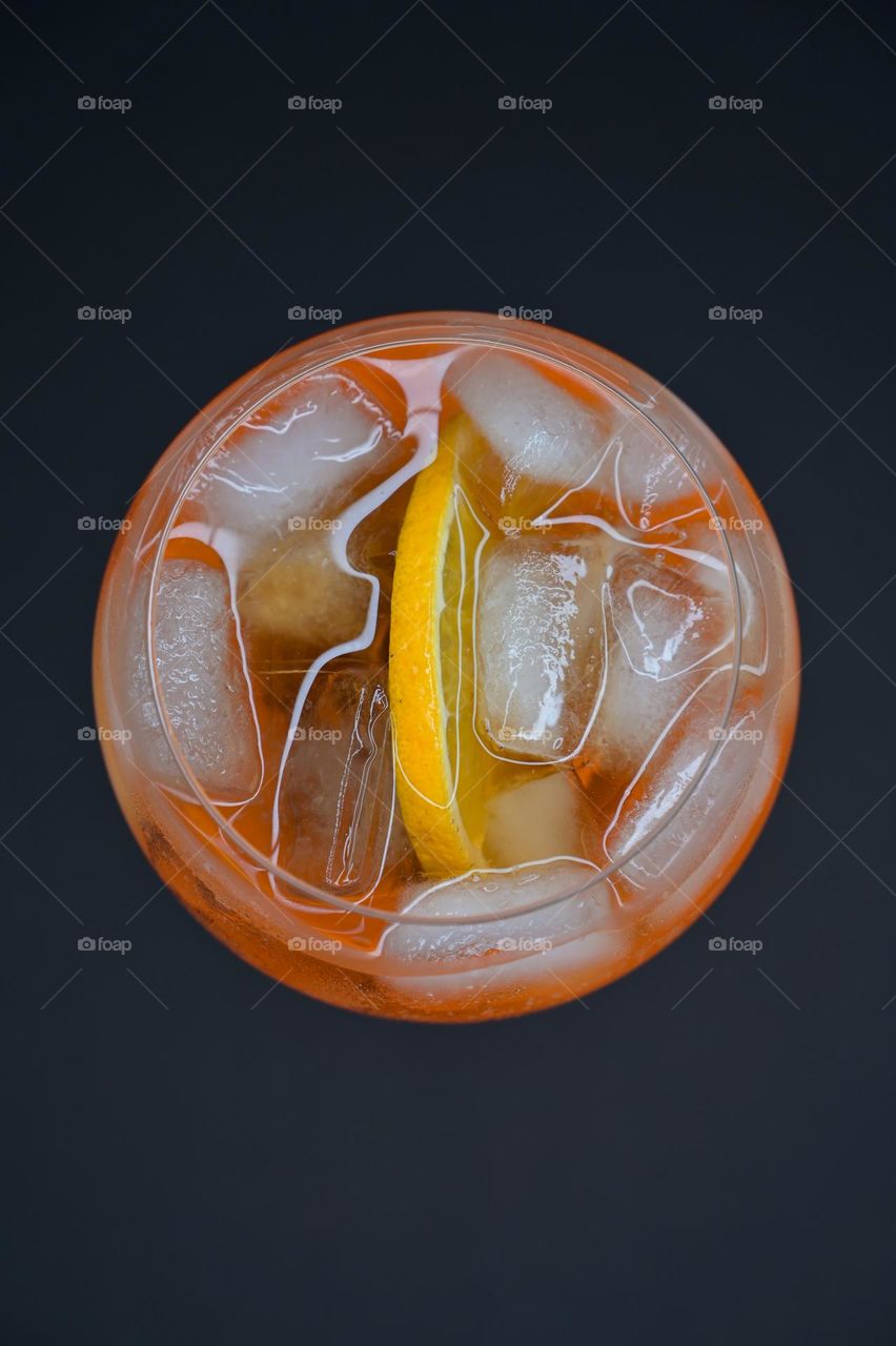 Top view orange cold drink with ice on black background