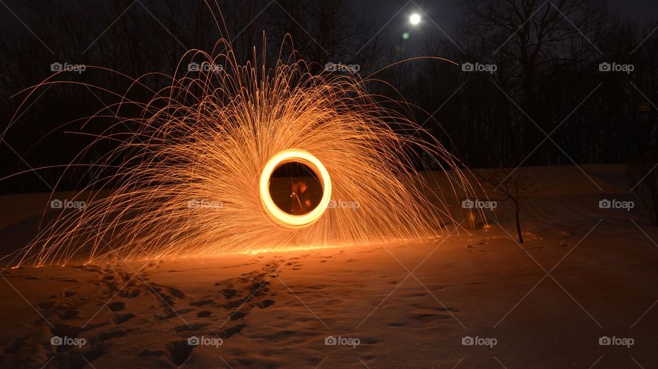 A man playing steel wool on the beach at night