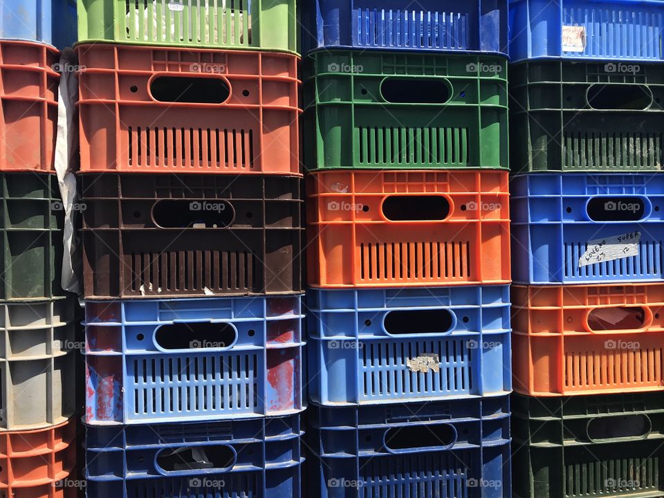 multi-colored plastic boxes for storing and transporting vegetables are stacked on each other together