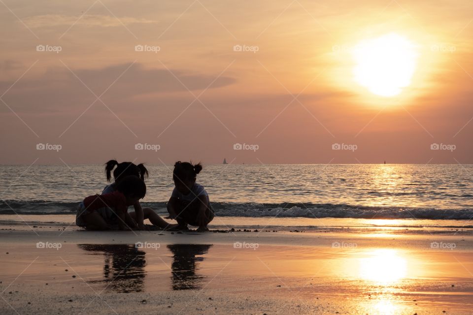 Three sisters play on the beautiful beach together in the sun set moment