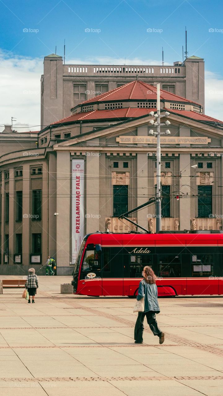 the tram arrives at a stop in front of a beautiful theater