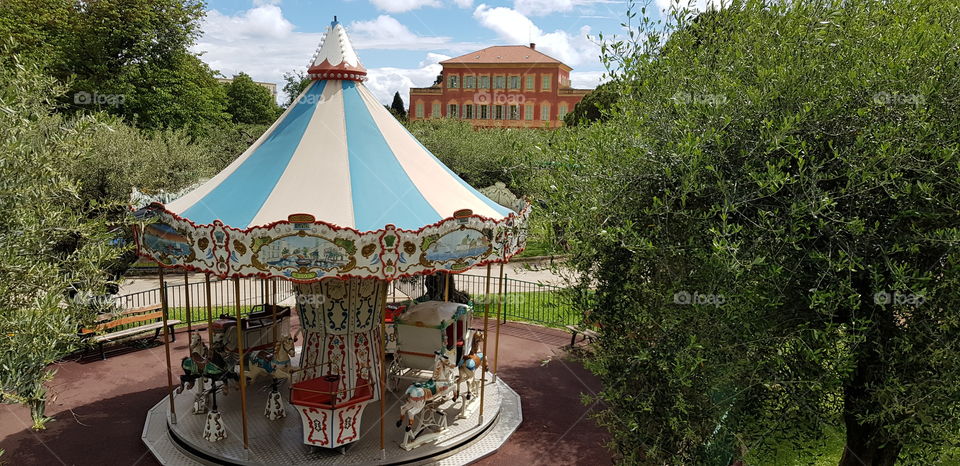 Beautiful traditional French carrousel with the Matisse museum in the background in Nice, France.