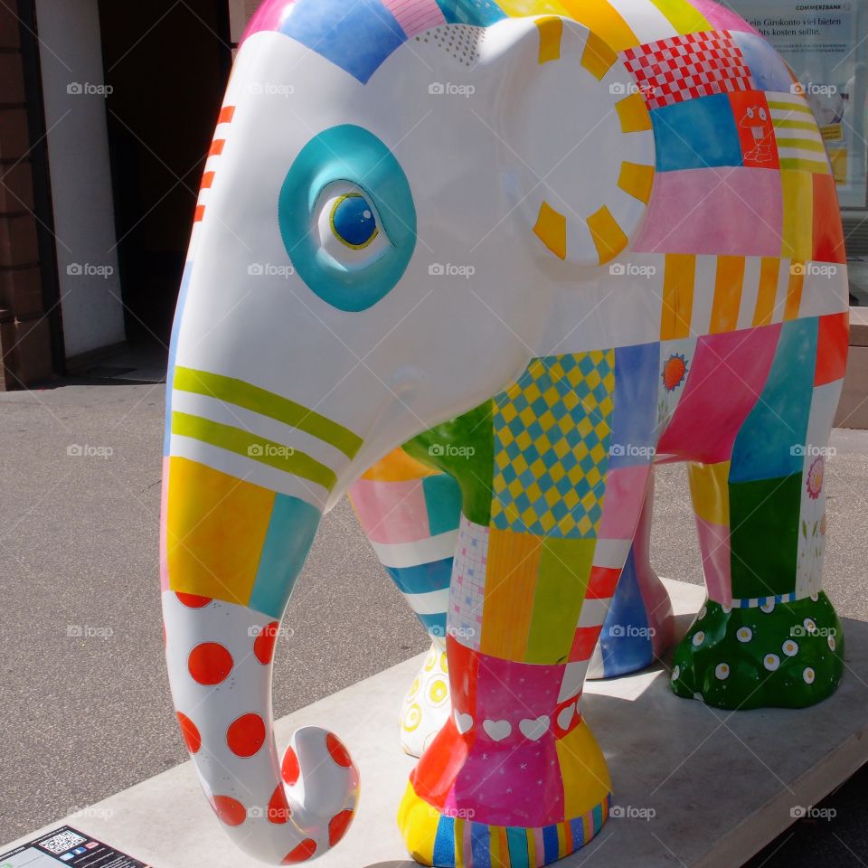 A large elephant statue with multiple colors and design patterns on it show the talent of an artist in a public square in Northwestern Germany on a sunny summer day.