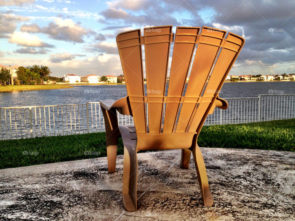 Chair in front if lake in backyard of house