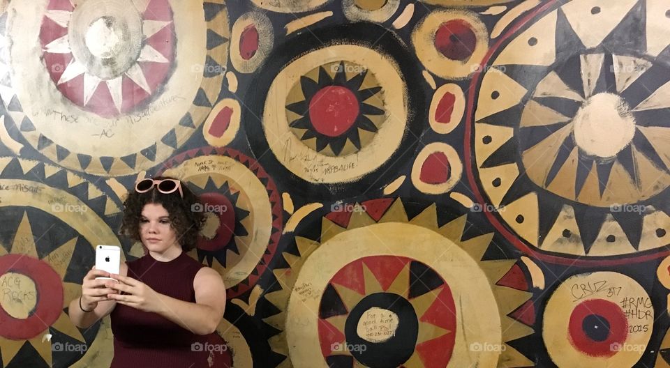 Woman standing against wall taking selfie